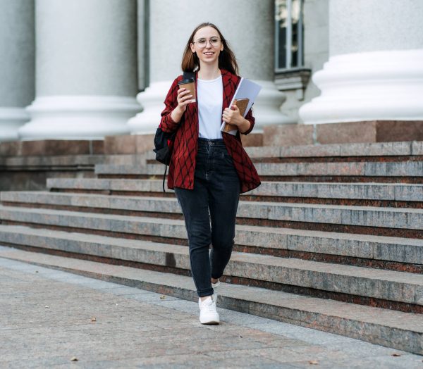 Scholarships for college students. Happy college student girl with laptop and books near college