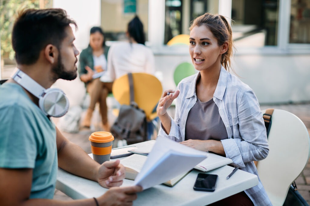 College student talking to her friends while learning together at campus.