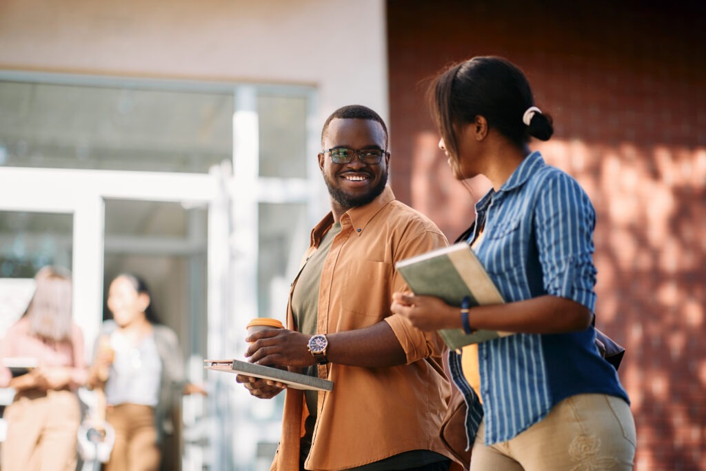 Happy African American students talking while walking on a class at the university.