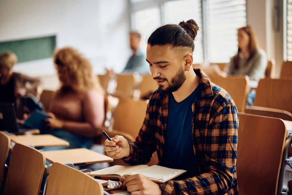 Male university student learning during a class at lecture hall.