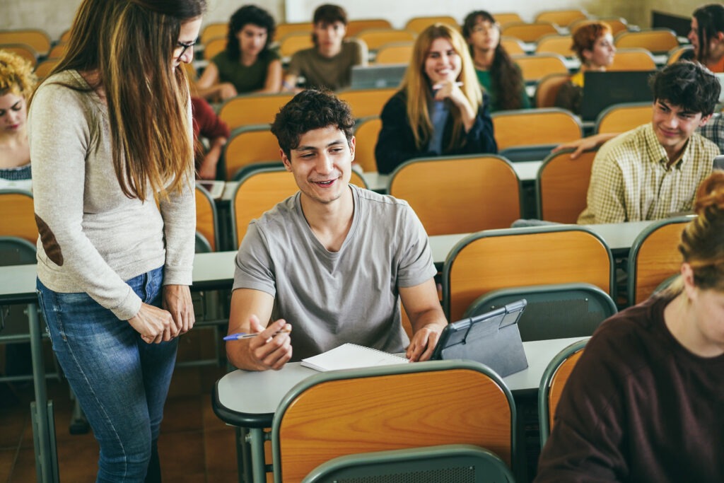 Mature teacher working with students inside classroom at school university - Focus on left guy face