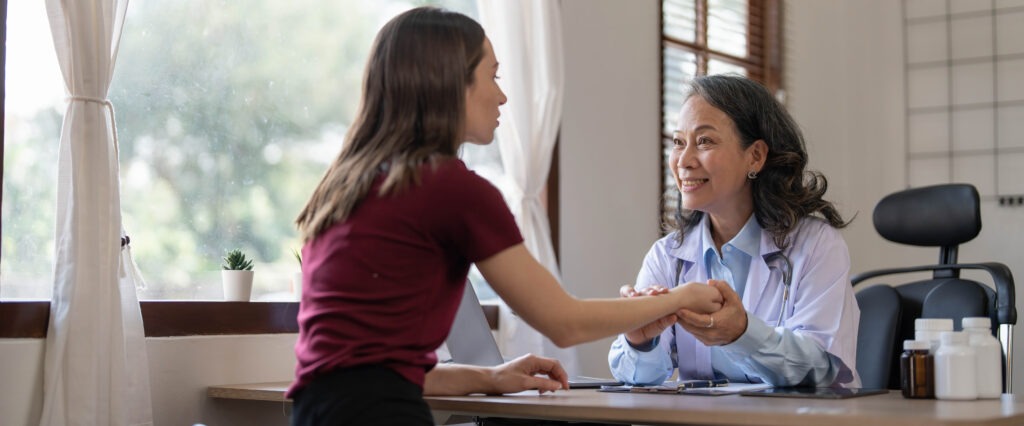 Middle aged female pediatrician listening to young woman's complaints with health problems And write