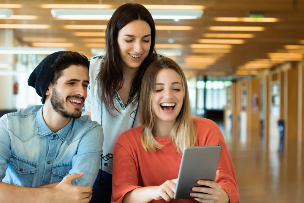 University students using digital tablet in university library.
