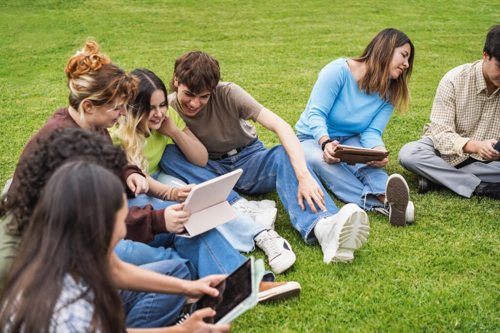 Young friends studying together outdoor sitting in university park - Focus on right girl face