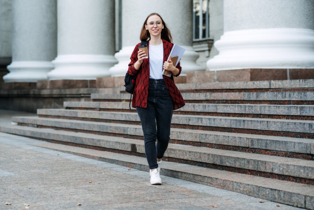 Scholarships for college students. Happy college student girl with laptop and books near college