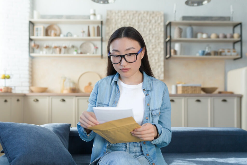 A young Asian student girl received a university admission letter in the mail. She holds an