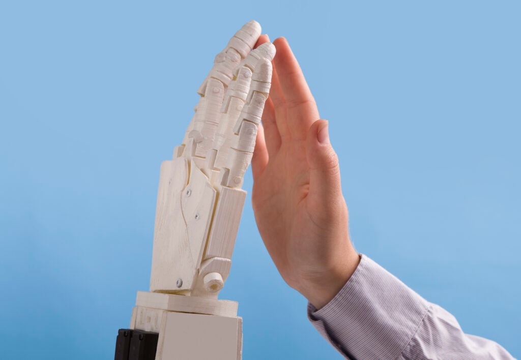 Human and robot hands giving high high on blue background