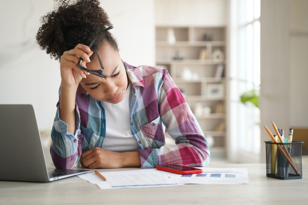 Mixed race school student girl studying with laptop at desk, preparing for exam. Academic stress