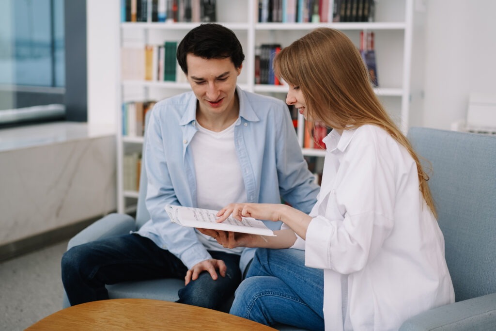 Attractive smiling happy skilled young couple of freelancers sitting at their workplace at home and