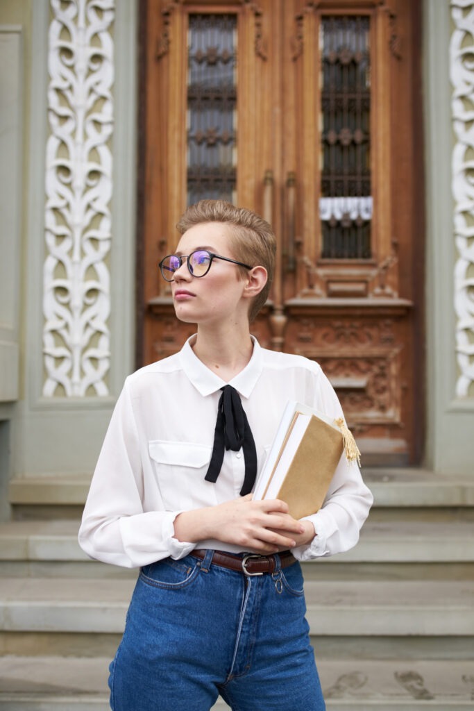 female student in glasses and jeans near the door on the street Institute of Education Faculty