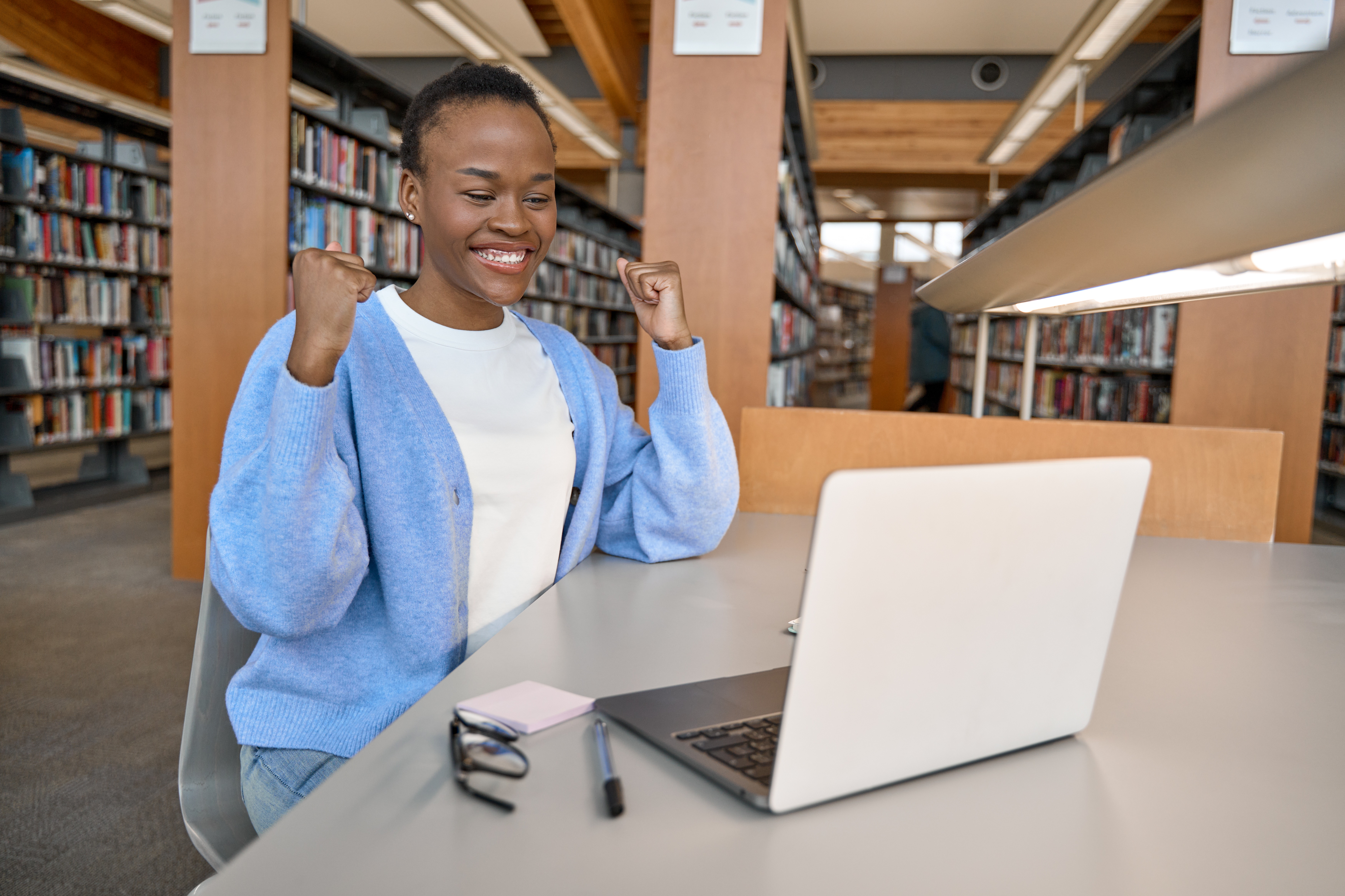 Happy excited African girl college student celebrating reading admission email.