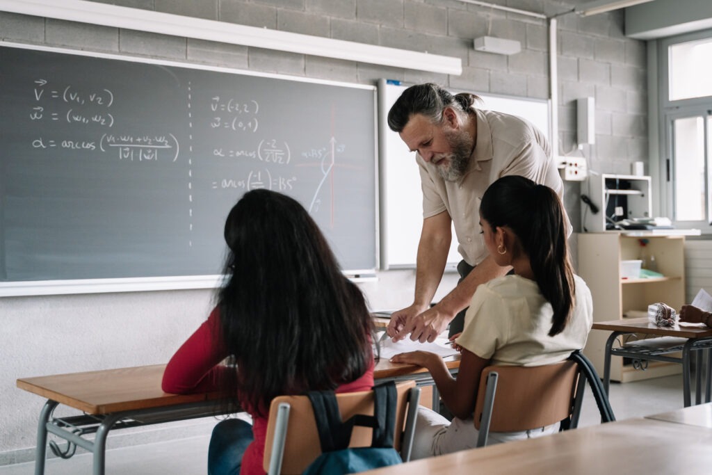 Teacher with beard helping latin student in class