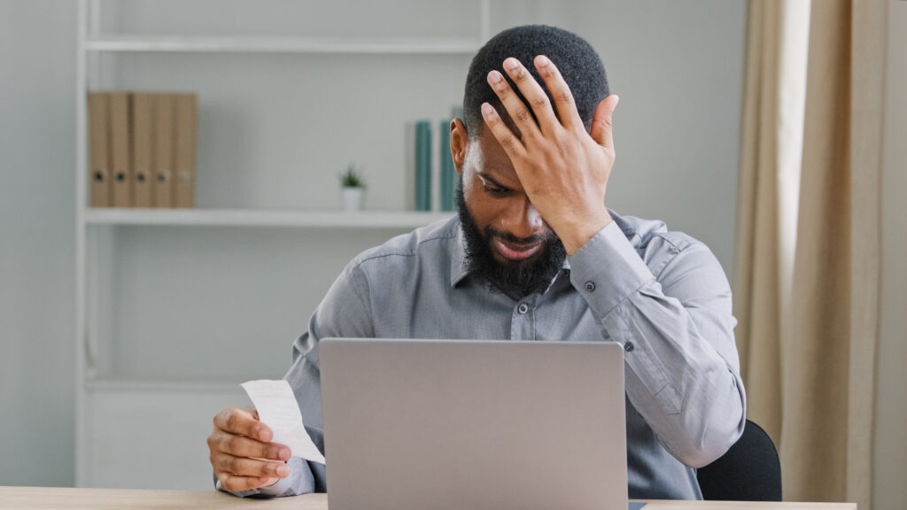 Angry sad upset African American ethnic man bearded businessman manage personal budget using