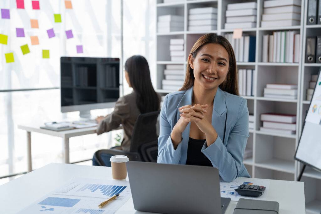 Confident Asian businesswoman smiling happily working on statistics paperwork financial business acc