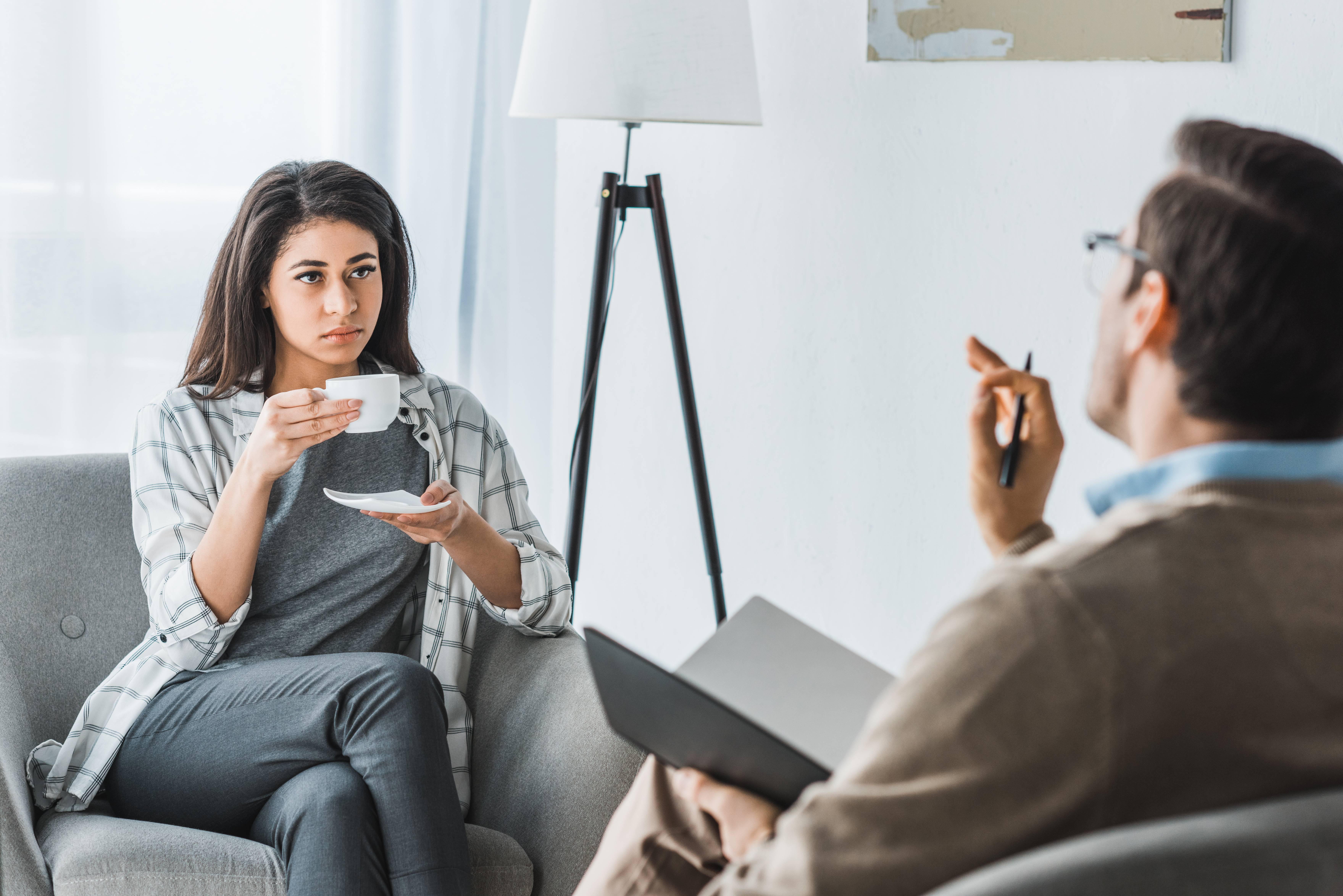 Woman drinking coffee and listening to male doctor recommendations