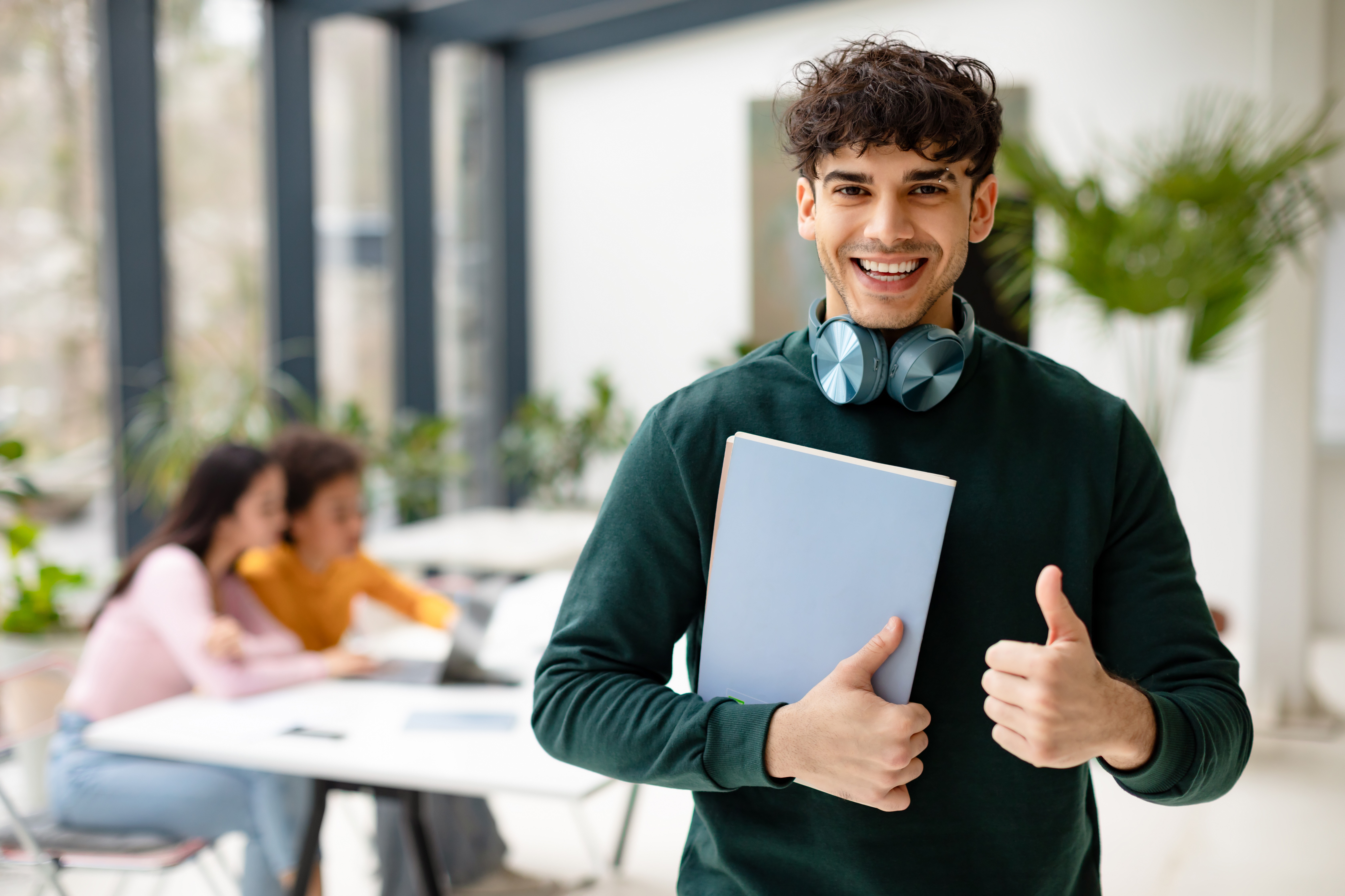 Academic success. Portrait of smiling european male student standing in modern classroom and showing