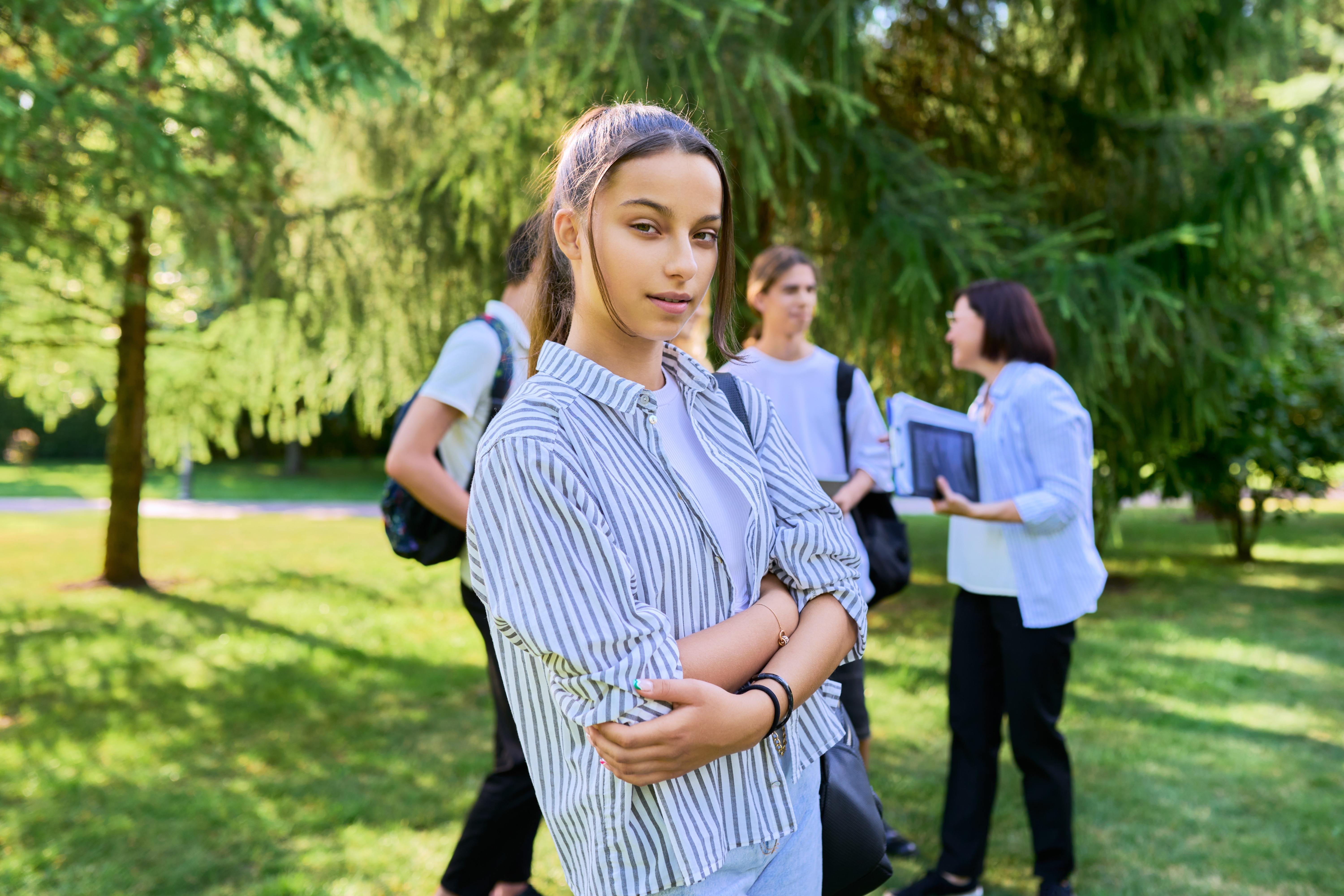 Female student 14, 15 years old with textbooks backpack, in school park