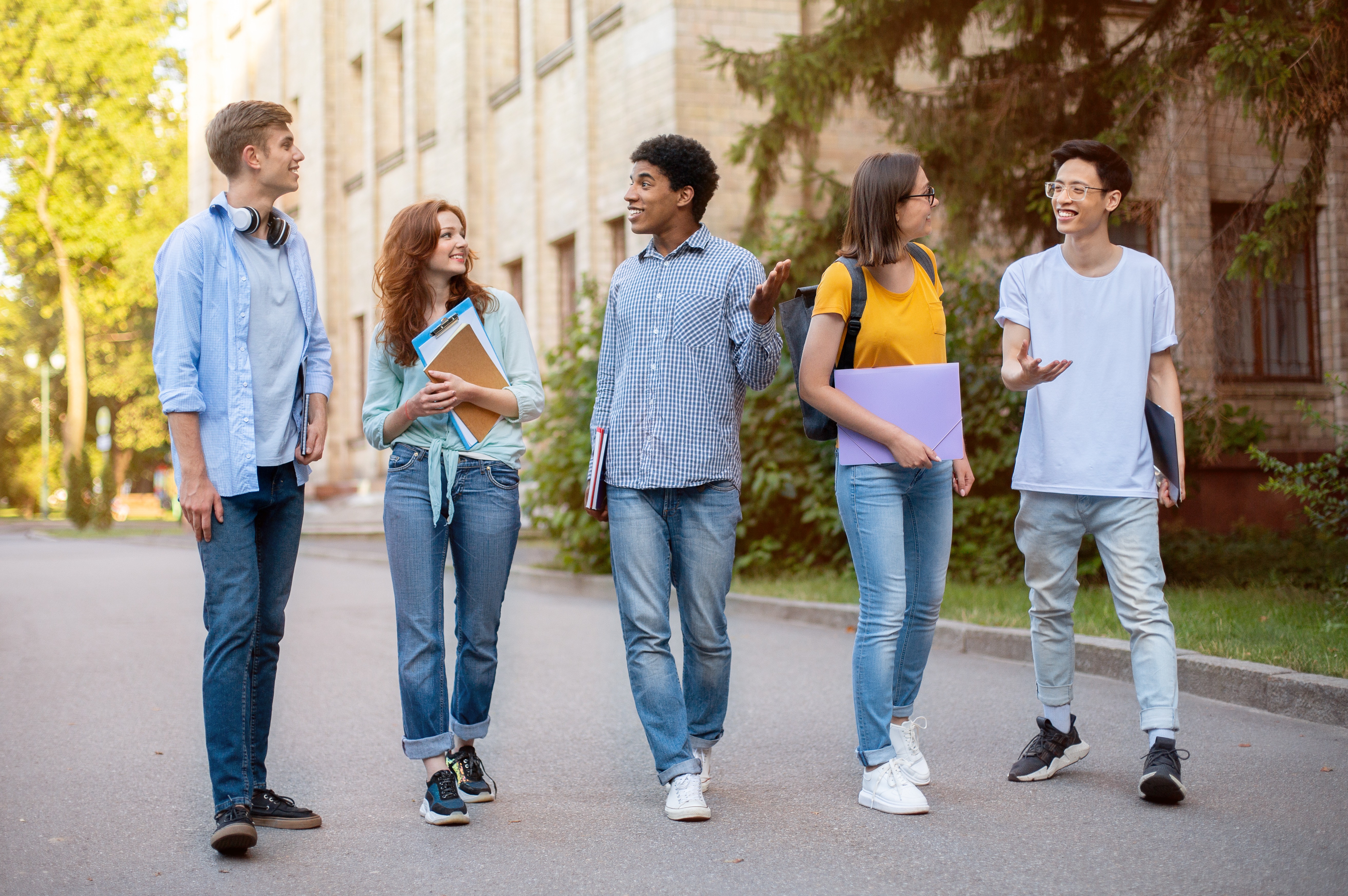 Group Of Multicultural First-Year Students Walking Near University Building Outside